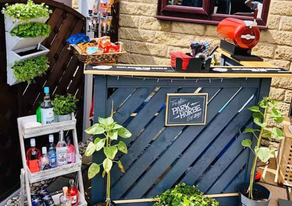 A garden bar with plants and a bottle of wine.