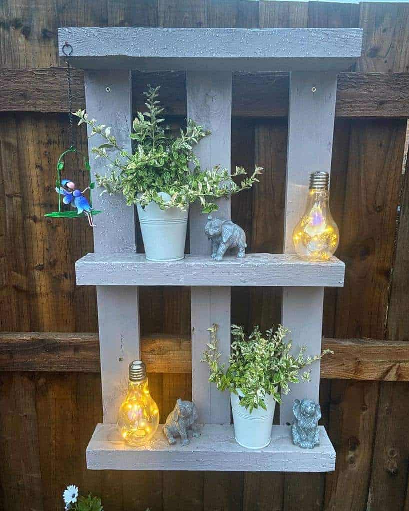 A wooden pallet shelf with potted plants and lights.