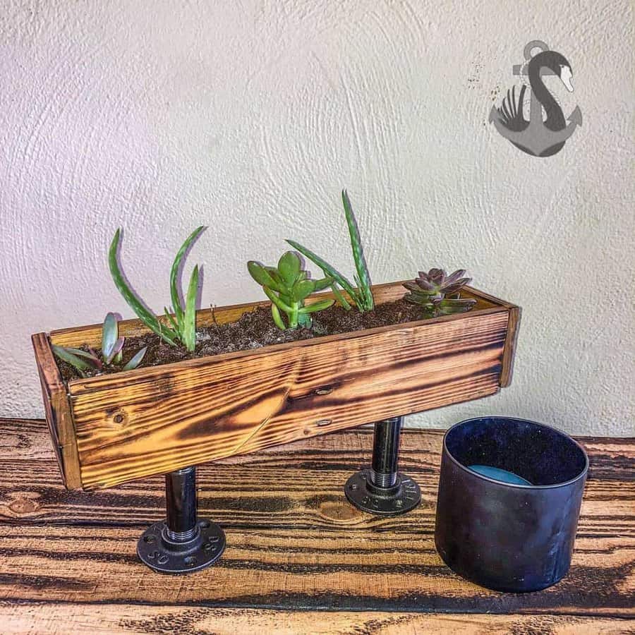 A wooden planter with a cactus and a candle.