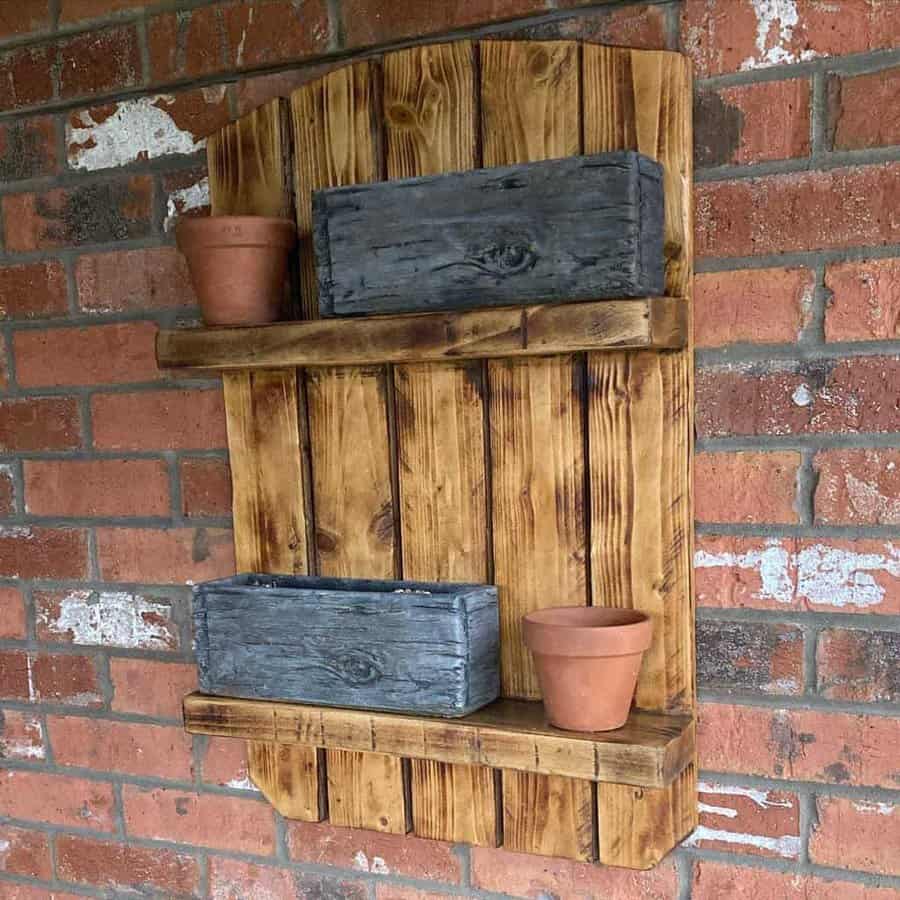 A wooden shelf with two potted plants on it.