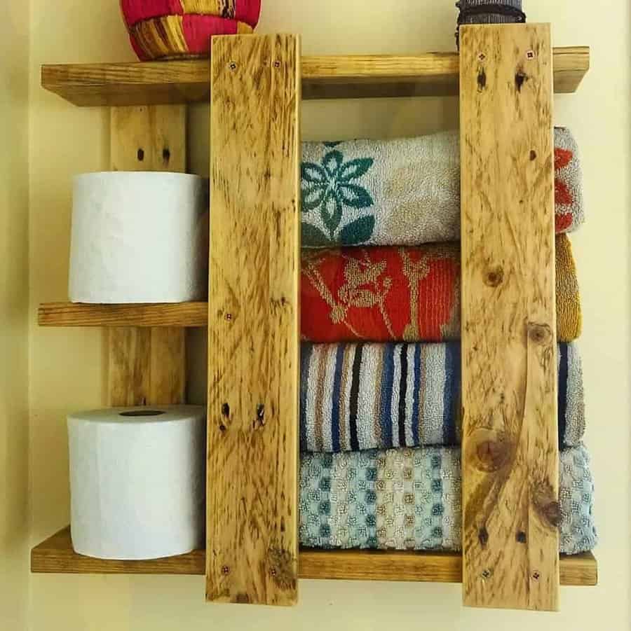 A wooden shelf with towels and toilet rolls on it.