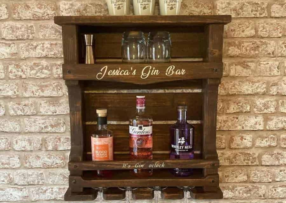 A wooden bar shelf with bottles and glasses on it.